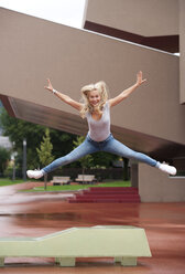 Portrait of blond teenage girl jumping in the air with outstretched arms and legs - WWF003764