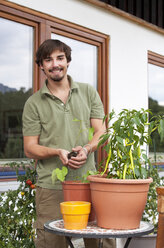 Portrait of smiling young man repotting plants - WWF003836