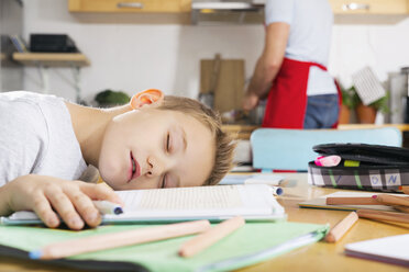 Junge sitzt am Küchentisch und schläft über seinem Schulbuch - PDF000687