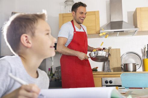 Father preparing food while his son doing his homework - PDF000696