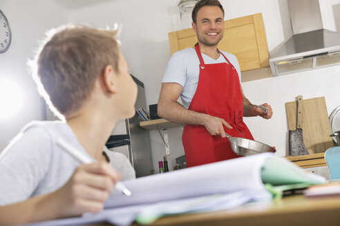 Father preparing food while his son doing his homework - PDF000697