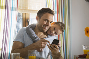 Vater und Sohn schauen auf ihr Smartphone - PDF000754