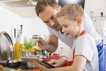 Vater und Sohn kochen gemeinsam mit einem digitalen Tablet - PDF000764