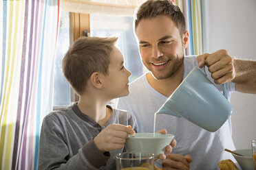 Vater gießt Milch in die Müslischale seines Sohnes - PDF000725