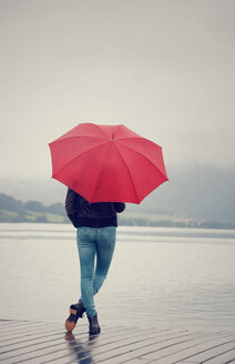 Österreich, Mondsee, junges Mädchen mit rotem Regenschirm am Seeufer stehend - WWF003778