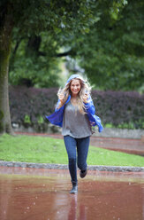 Austria, Thalgau, smiling teenage girl running in the rain - WWF003783