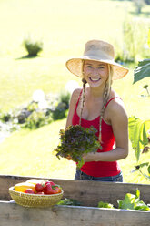 Portrait of smiling teenage girl holding head of lettuce - WWF003812