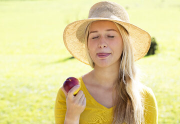 Porträt eines lächelnden Teenagers, der einen Pfirsich isst - WWF003816