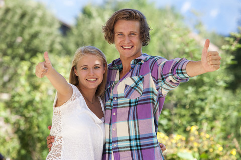 Porträt eines lächelnden jungen Paares mit Daumen nach oben, lizenzfreies Stockfoto