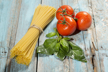 Spaghetti, Basilikum und Tomaten auf Holz - MAEF009694