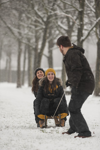 Drei Freunde haben Spaß mit dem Schlitten im Winter, lizenzfreies Stockfoto