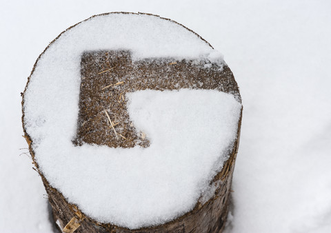 Abdruck einer Axt auf einem schneebedeckten Holzscheit, lizenzfreies Stockfoto