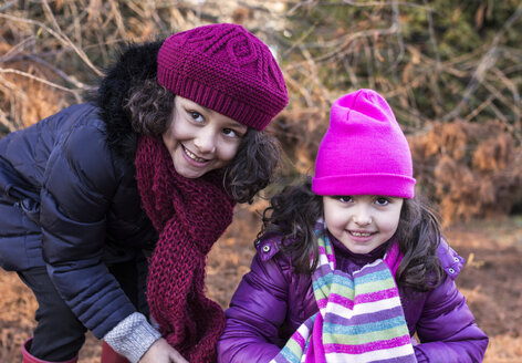 Porträt von zwei lächelnden kleinen Mädchen in einem Park an einem Wintertag - MGOF000053