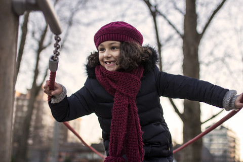 Porträt eines glücklichen kleinen Mädchens auf einem Spielplatz an einem Wintertag, lizenzfreies Stockfoto