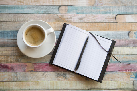 Tasse Kaffee und aufgeschlagenes Notizbuch, lizenzfreies Stockfoto