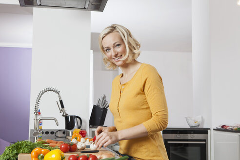 Lächelnde Frau beim Kochen in der Küche - RBF002367