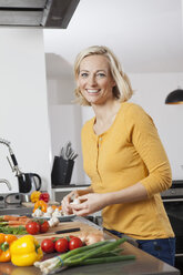 Lächelnde Frau beim Kochen in der Küche - RBF002368