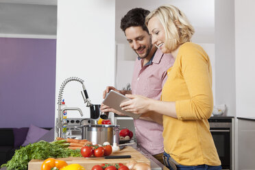 Couple cooking in kitchen using digital tablet - RBF002429