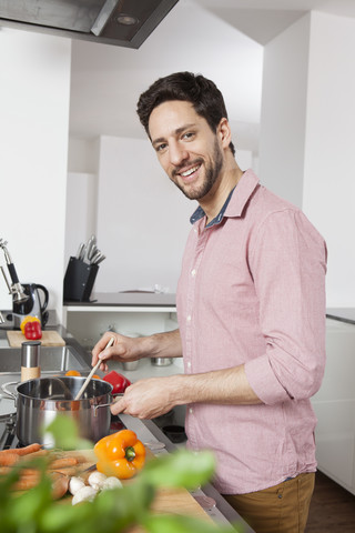 Lächelnder Mann beim Kochen in der Küche, lizenzfreies Stockfoto