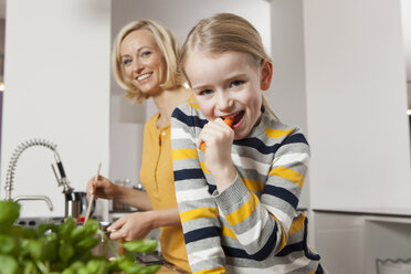 Mutter mit Tochter isst Karotte in der Küche - RBF002386