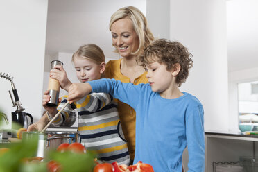 Mother, daughter and son cooking in kitchen - RBF002396