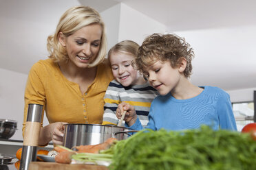 Mother, daughter and son cooking in kitchen - RBF002397