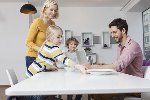 Familie deckt den Tisch mit dem Vater am Laptop - RBF002410