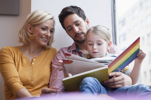 Vater und Mutter lesen ihrer Tochter ein Bilderbuch vor - RBF002411