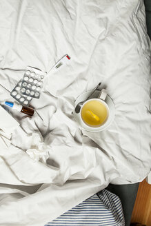 Zitronentee, Thermometer, Tabletten, Nasenspray und Taschentücher im Bett - SBDF001606