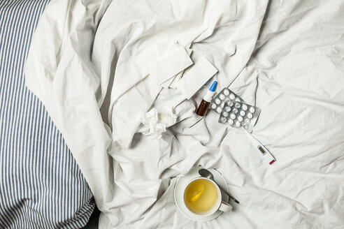 Zitronentee, Thermometer, Tabletten, Nasenspray und Taschentücher im Bett - SBDF001607