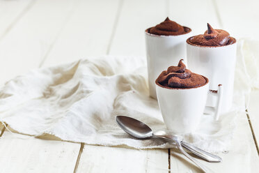 Three cups of vegan mousse au chocolat, tea spoons, cloth on white wood - SBDF001596