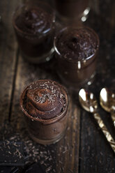 Glasses of vegan mousse au chocolat and tea spoons on wood - SBDF001598