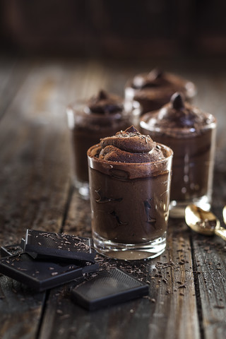 Gläser mit veganer Mousse au Chocolat und Zartbitterschokolade auf Holz, lizenzfreies Stockfoto