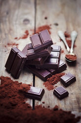 Zartbitterschokolade, Teelöffel und Kakaopulver auf Holz - CZF000191