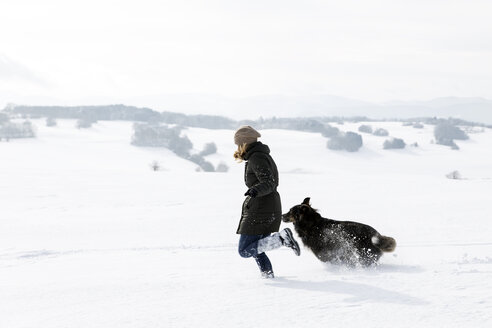 Deutschland, Baden-Württemberg, Waldshut-Tiengen, Frau und Hund laufen im Schnee - MIDF000055