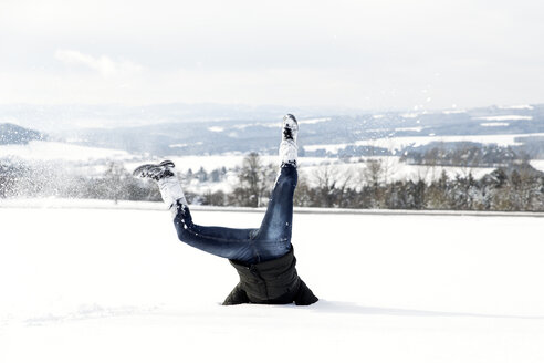 Deutschland, Baden-Württemberg, Waldshut-Tiengen, verspielte Frau im Schnee beim Kopfstand - MIDF000050