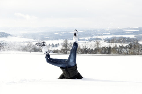 Germany, Baden-Wuerttemberg, Waldshut-Tiengen, playful woman in snow doing a headstand - MIDF000050