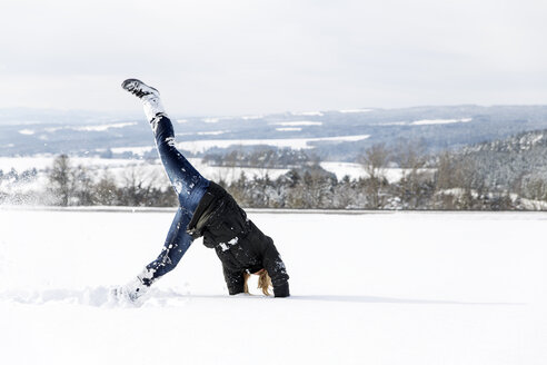 Germany, Baden-Wuerttemberg, Waldshut-Tiengen, playful woman in snow doing a cartwheel - MIDF000052