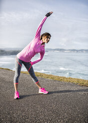 Spain, Gijon, sportive young woman exercising at the coast - MGOF000088