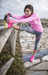 Spain, Gijon, sportive young woman stretching - MGOF000098