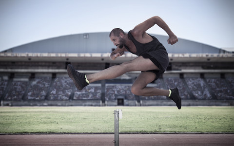 Athlet springt über Hürde, lizenzfreies Stockfoto