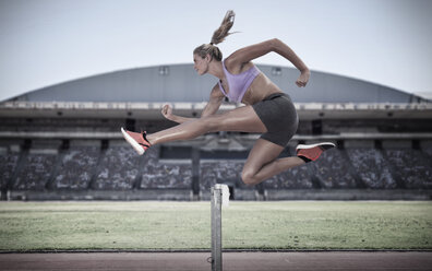 Athlete jumping over hurdle - ZEF007478