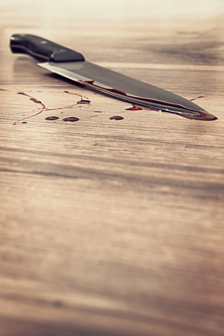 Blood stained knife on wooden floor stock photo