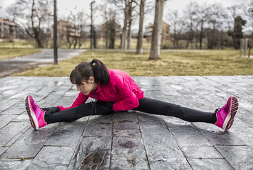 Spain, Young woman warming up in park - MGOF000131