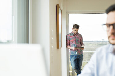 Junger Mann am Fenster mit digitalem Tablet - UUF003328