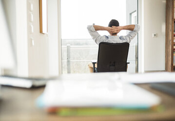 Man sitting on office chair looking out of window - UUF003334