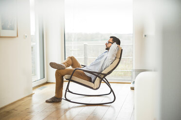 Young man sitting on rocking chair relaxing - UUF003335