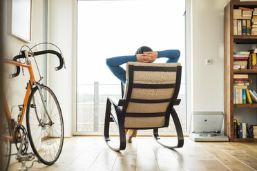 Mann sitzt auf einem Schaukelstuhl und schaut aus dem Fenster - UUF003344