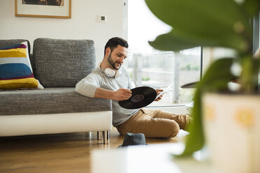 Young man at home looking at record - UUF003345