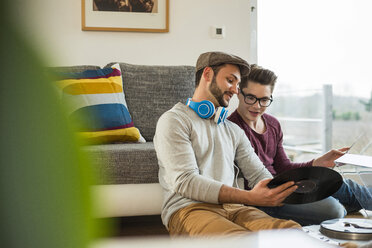 Zwei junge Männer, die zu Hause über Schallplatten diskutieren - UUF003350